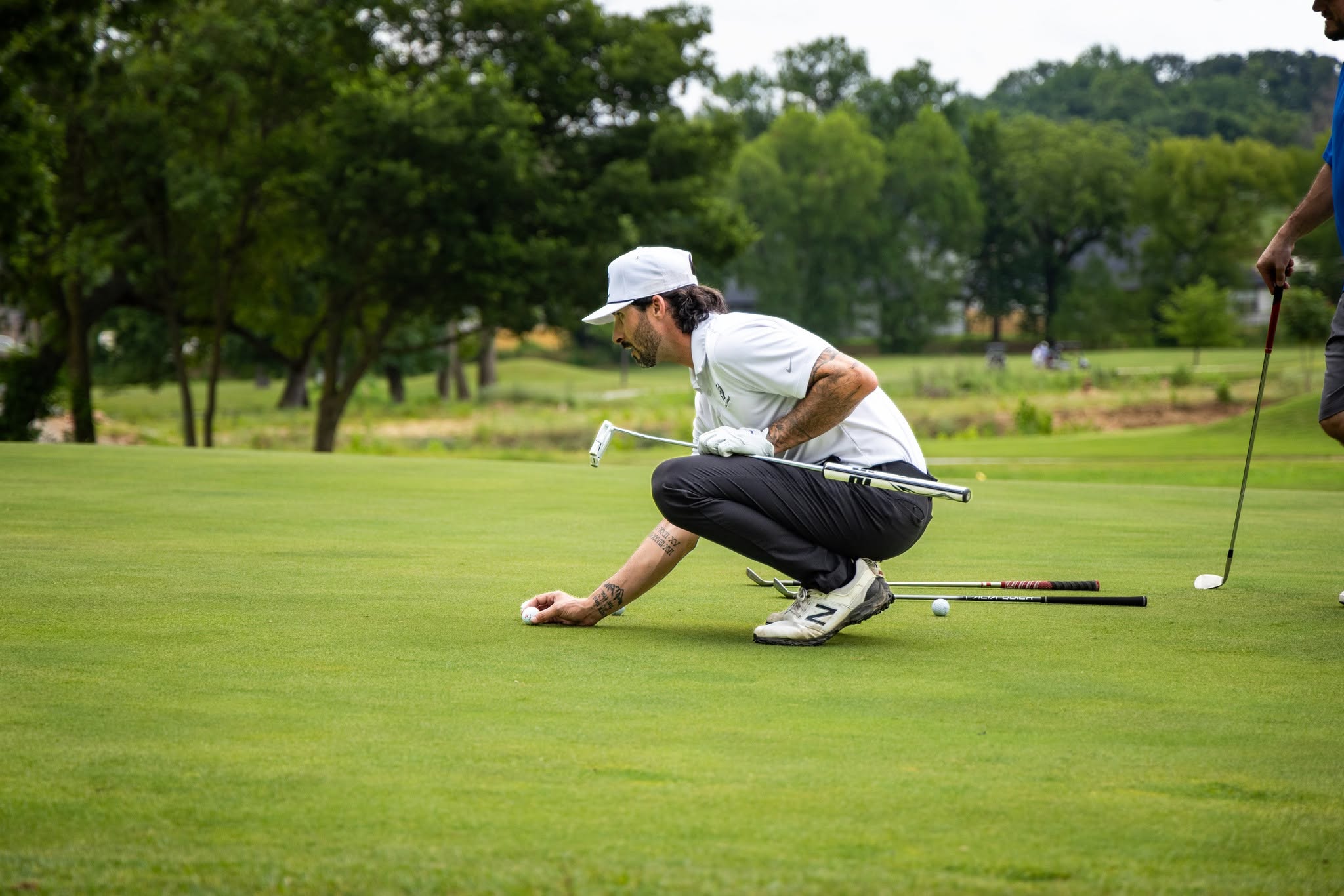 A golfer crouching to read the line on the green at The Creeks championship course