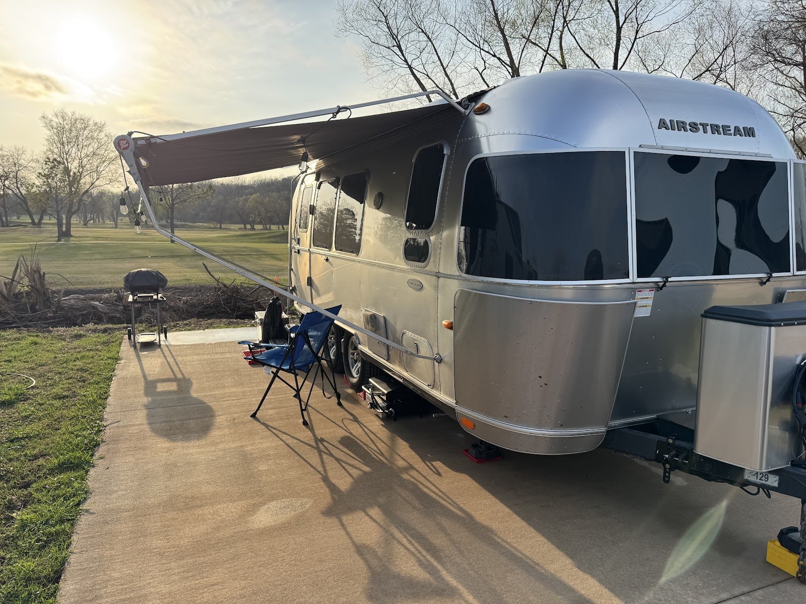 A gleaming Airstream trailer on a full-hookup pad at golden hour at The Creeks