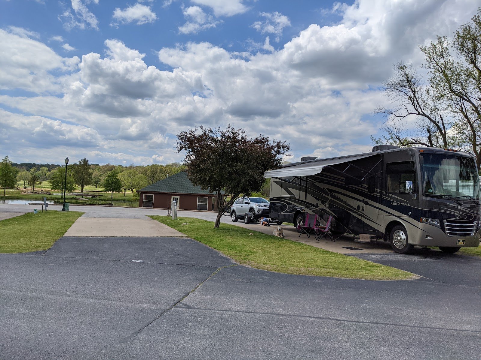 A big Class-A motorhome with its awning out on a wide concrete pad at The Creeks